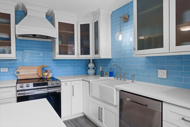 kitchen featuring white cabinets, stainless steel appliances, hanging light fixtures, and custom range hood