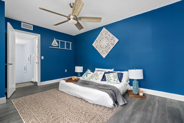 bedroom with ceiling fan, dark hardwood / wood-style flooring, and a textured ceiling