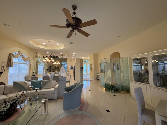 living room with ceiling fan, light tile patterned floors, a tray ceiling, and ornamental molding