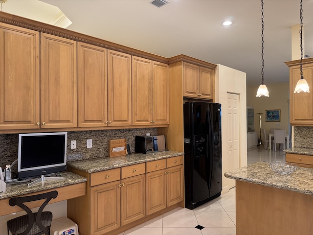 kitchen with decorative light fixtures, tasteful backsplash, black fridge, light tile patterned floors, and stone countertops