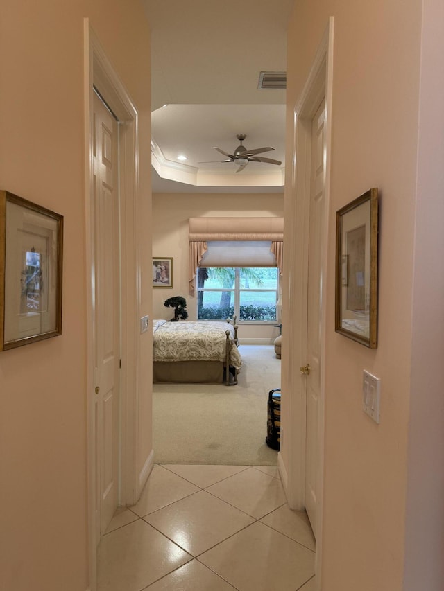 hallway featuring a raised ceiling and light colored carpet