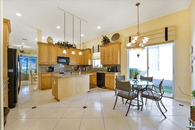 kitchen featuring light stone counters, a center island with sink, pendant lighting, decorative backsplash, and black appliances