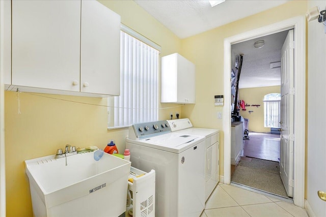 clothes washing area featuring sink, light tile patterned floors, cabinets, washer and dryer, and a textured ceiling