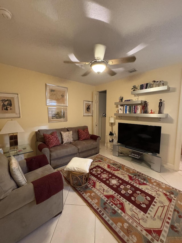 living room with ceiling fan, light tile patterned floors, and a textured ceiling