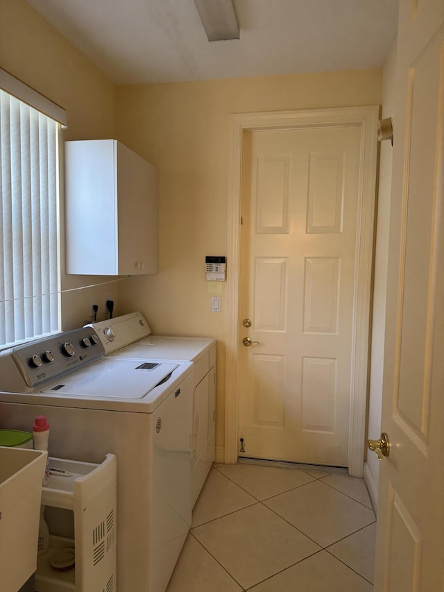 washroom with light tile patterned floors, washing machine and dryer, and cabinets