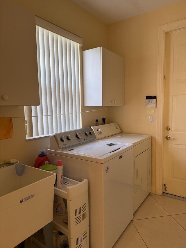 washroom featuring light tile patterned floors, cabinets, and washer and dryer