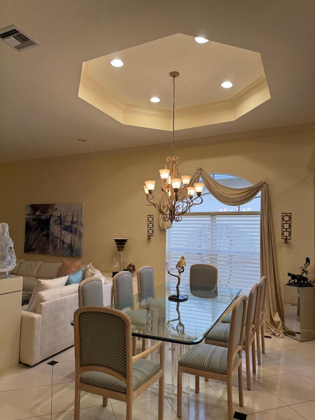 dining area with light tile patterned floors, a tray ceiling, crown molding, and an inviting chandelier