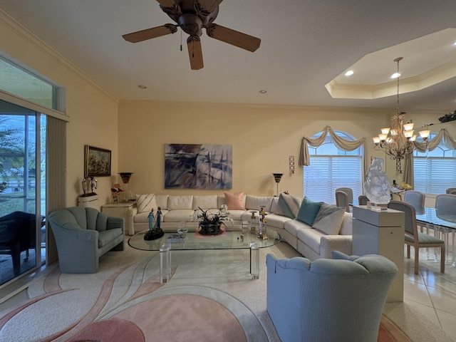 living room featuring ornamental molding, ceiling fan with notable chandelier, and a raised ceiling