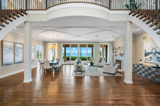 living room with dark hardwood / wood-style flooring, crown molding, a high ceiling, and ornate columns