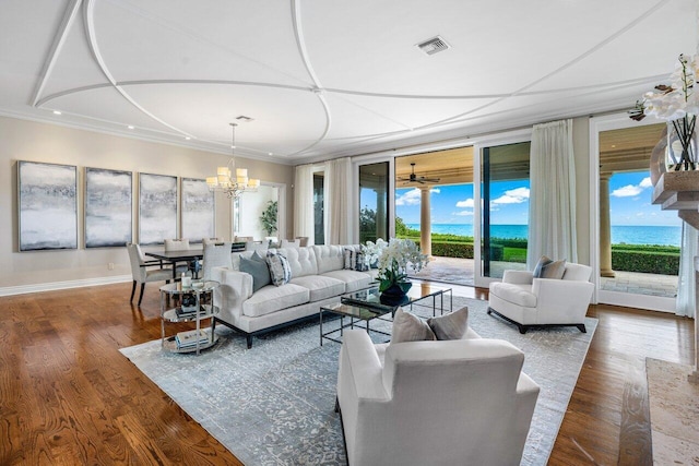 living room featuring hardwood / wood-style floors, crown molding, a chandelier, and a water view