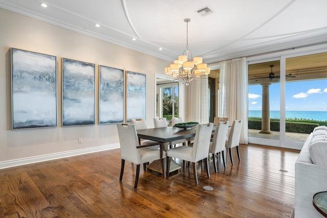 dining area featuring ornamental molding, a water view, hardwood / wood-style floors, and a notable chandelier