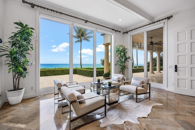 living room with a water view, crown molding, decorative columns, and beamed ceiling