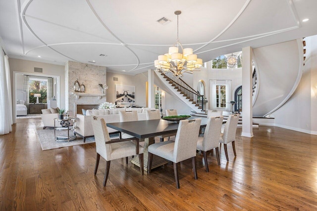 dining area featuring a large fireplace, a chandelier, and hardwood / wood-style floors