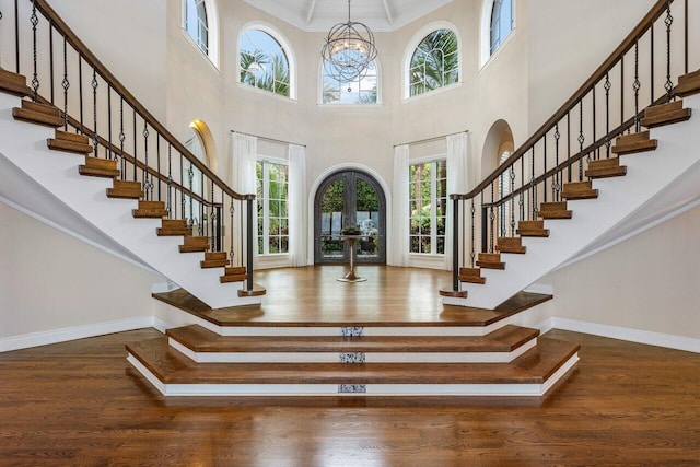 foyer entrance with ornamental molding, hardwood / wood-style floors, a notable chandelier, and french doors