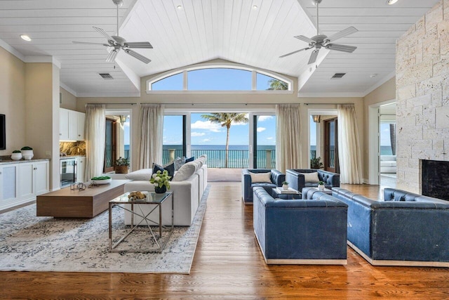 living room featuring crown molding, ceiling fan, hardwood / wood-style floors, a water view, and a fireplace