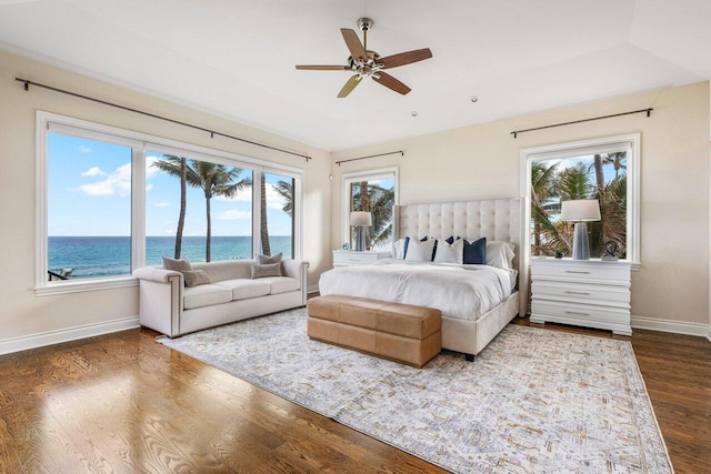 bedroom with dark hardwood / wood-style floors and a water view