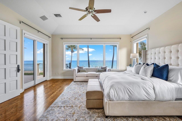 bedroom with access to exterior, hardwood / wood-style flooring, ceiling fan, and a water view