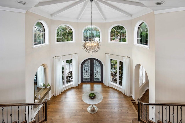 foyer entrance featuring plenty of natural light, a notable chandelier, beam ceiling, and french doors