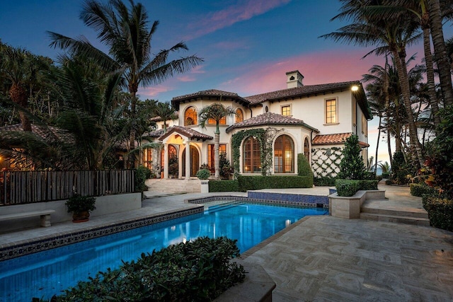 back house at dusk featuring a patio