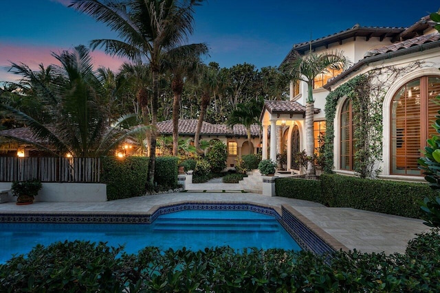 pool at dusk featuring a patio