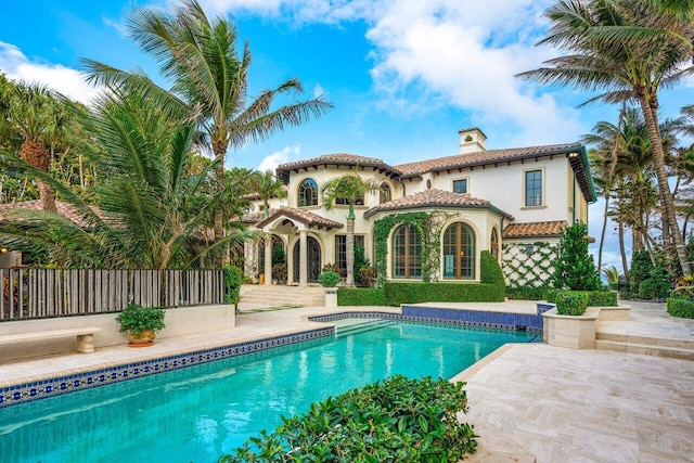 back of property featuring a fenced in pool and a patio