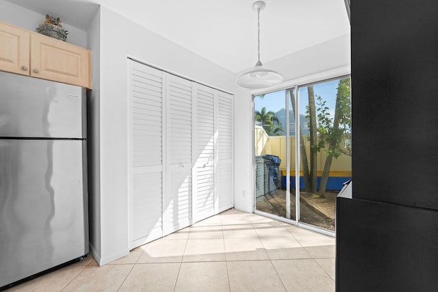 interior space featuring access to exterior, a closet, stainless steel fridge, and light tile patterned floors