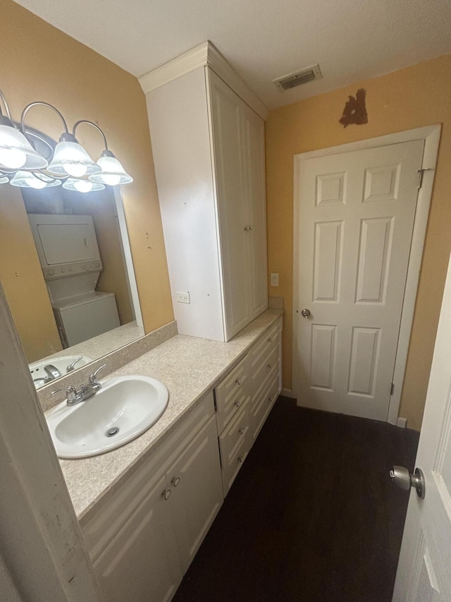 bathroom featuring stacked washer / dryer and vanity