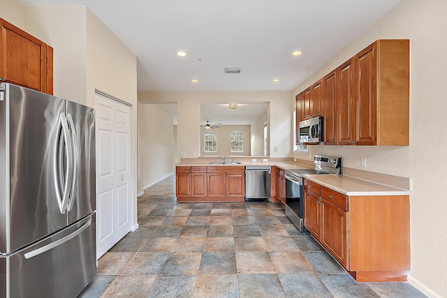 kitchen with brown cabinetry, appliances with stainless steel finishes, light countertops, and a sink