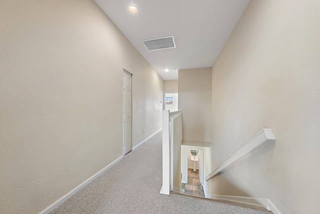 hall with carpet, an upstairs landing, visible vents, and baseboards