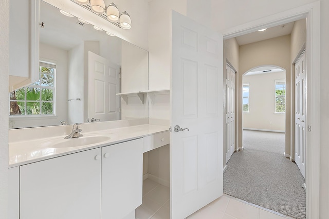 bathroom with vanity, plenty of natural light, baseboards, and tile patterned flooring