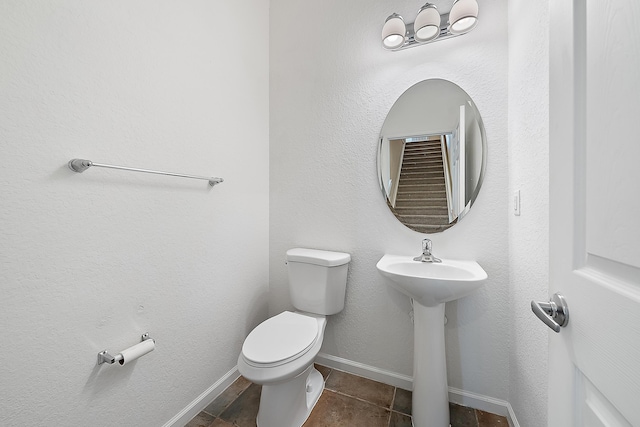 half bathroom featuring toilet, baseboards, and a sink