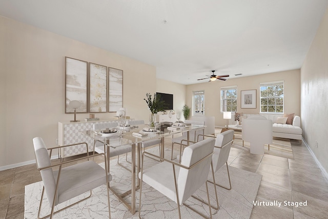 dining space with light tile patterned flooring, visible vents, a ceiling fan, and baseboards