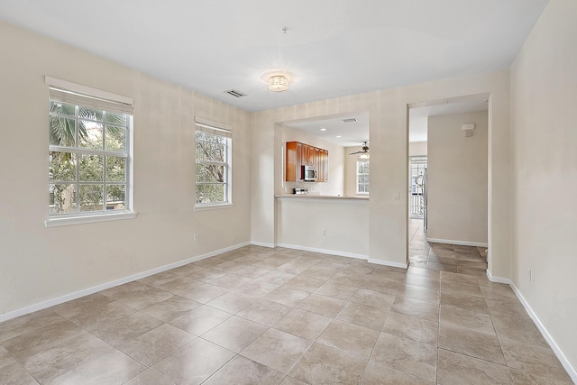 unfurnished living room with light tile patterned floors, visible vents, and baseboards