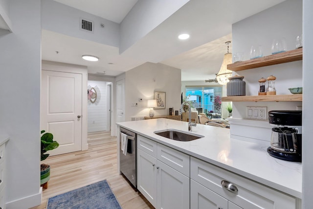 kitchen with decorative light fixtures, white cabinetry, light hardwood / wood-style floors, sink, and stainless steel dishwasher