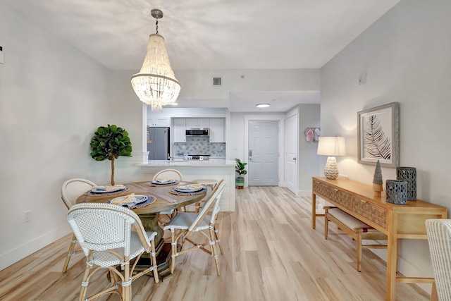 dining area featuring light hardwood / wood-style floors and a notable chandelier