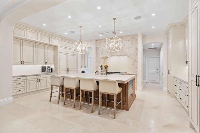 kitchen with cream cabinetry, an island with sink, and pendant lighting