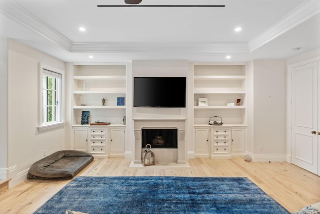 living room featuring light wood-type flooring, built in features, and a tray ceiling