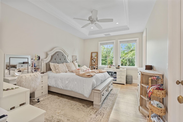 bedroom with ceiling fan, a tray ceiling, light hardwood / wood-style flooring, and ornamental molding