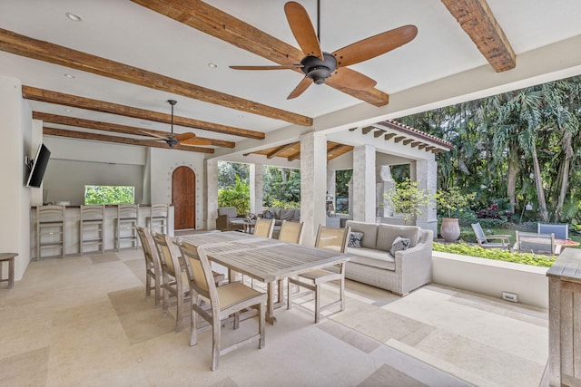 sunroom / solarium featuring ceiling fan and beamed ceiling