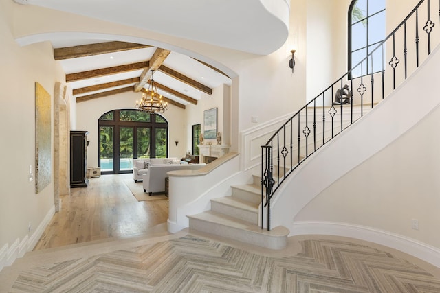 entrance foyer featuring light parquet flooring, french doors, an inviting chandelier, high vaulted ceiling, and beam ceiling