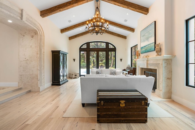 living room with beam ceiling, high vaulted ceiling, a high end fireplace, and light hardwood / wood-style flooring