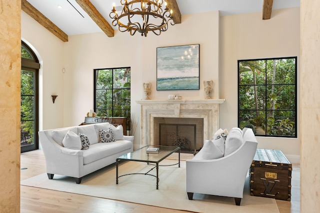 living room featuring light hardwood / wood-style flooring, an inviting chandelier, beamed ceiling, and a fireplace