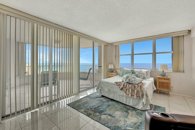 bedroom with a wall of windows, access to outside, tile patterned floors, a textured ceiling, and a water view