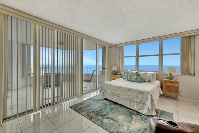 tiled bedroom with a textured ceiling, floor to ceiling windows, access to exterior, and a water view