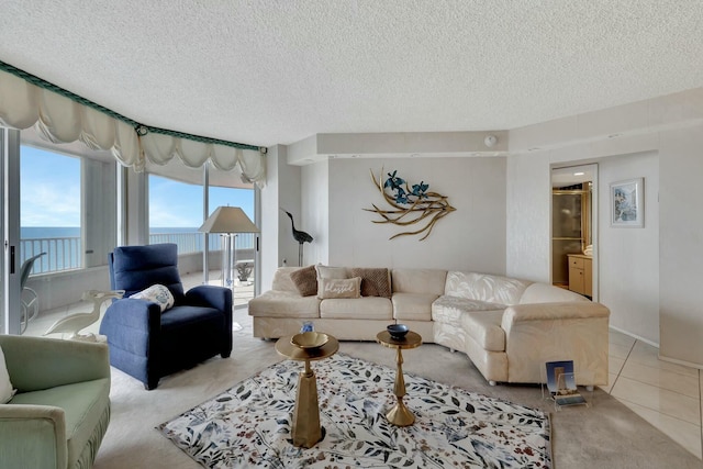 living room featuring a textured ceiling, light tile patterned floors, and a water view