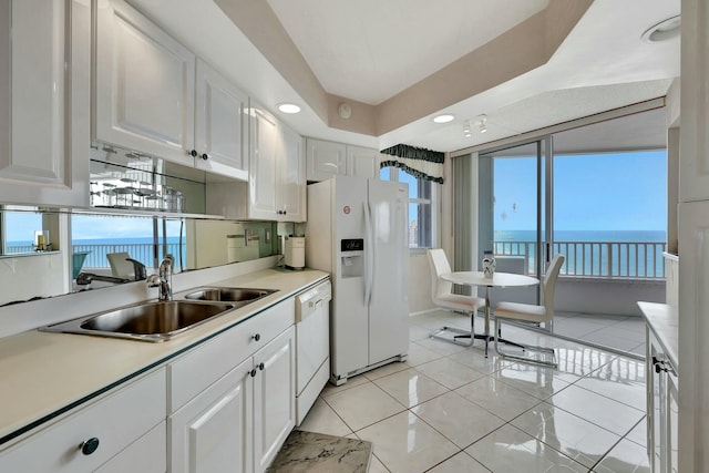 kitchen featuring sink, white appliances, white cabinetry, light tile patterned flooring, and a water view