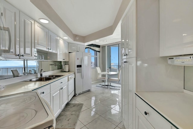 kitchen featuring sink, white appliances, and white cabinetry