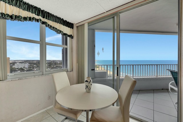 tiled dining area featuring a water view and a beach view