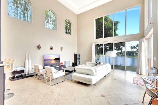 living room featuring light tile patterned flooring, a healthy amount of sunlight, and a high ceiling