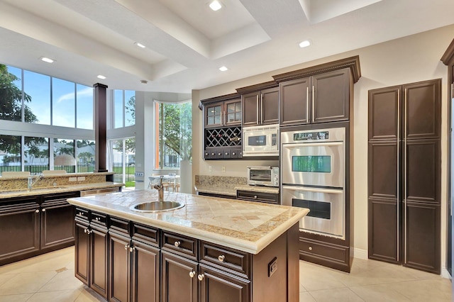 kitchen with appliances with stainless steel finishes, a center island with sink, a tray ceiling, and sink